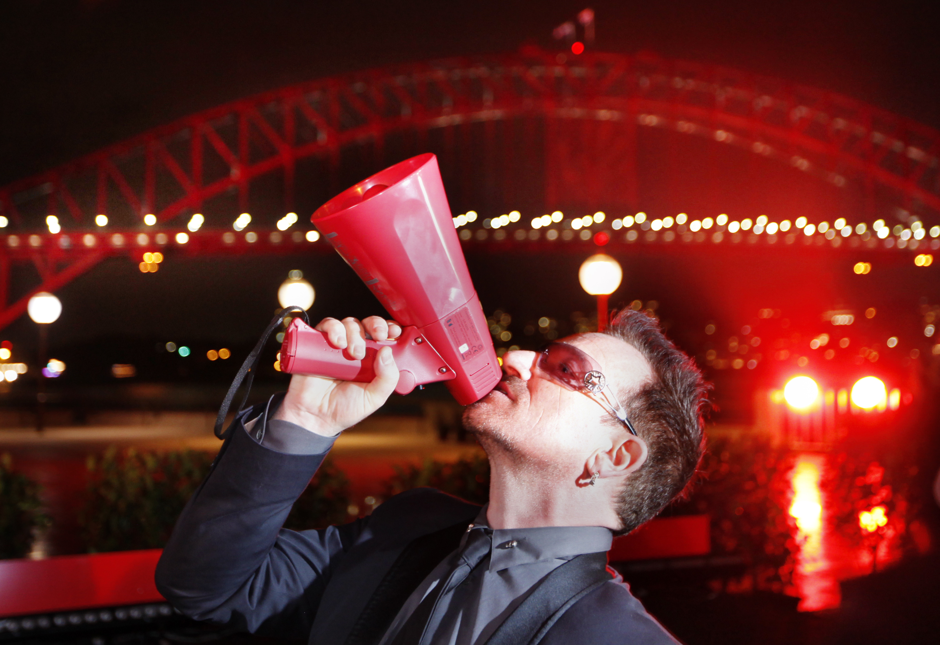 Bono poses for photographers in front of the Sydney Harbour Bridge at an event to launch World Aids Day